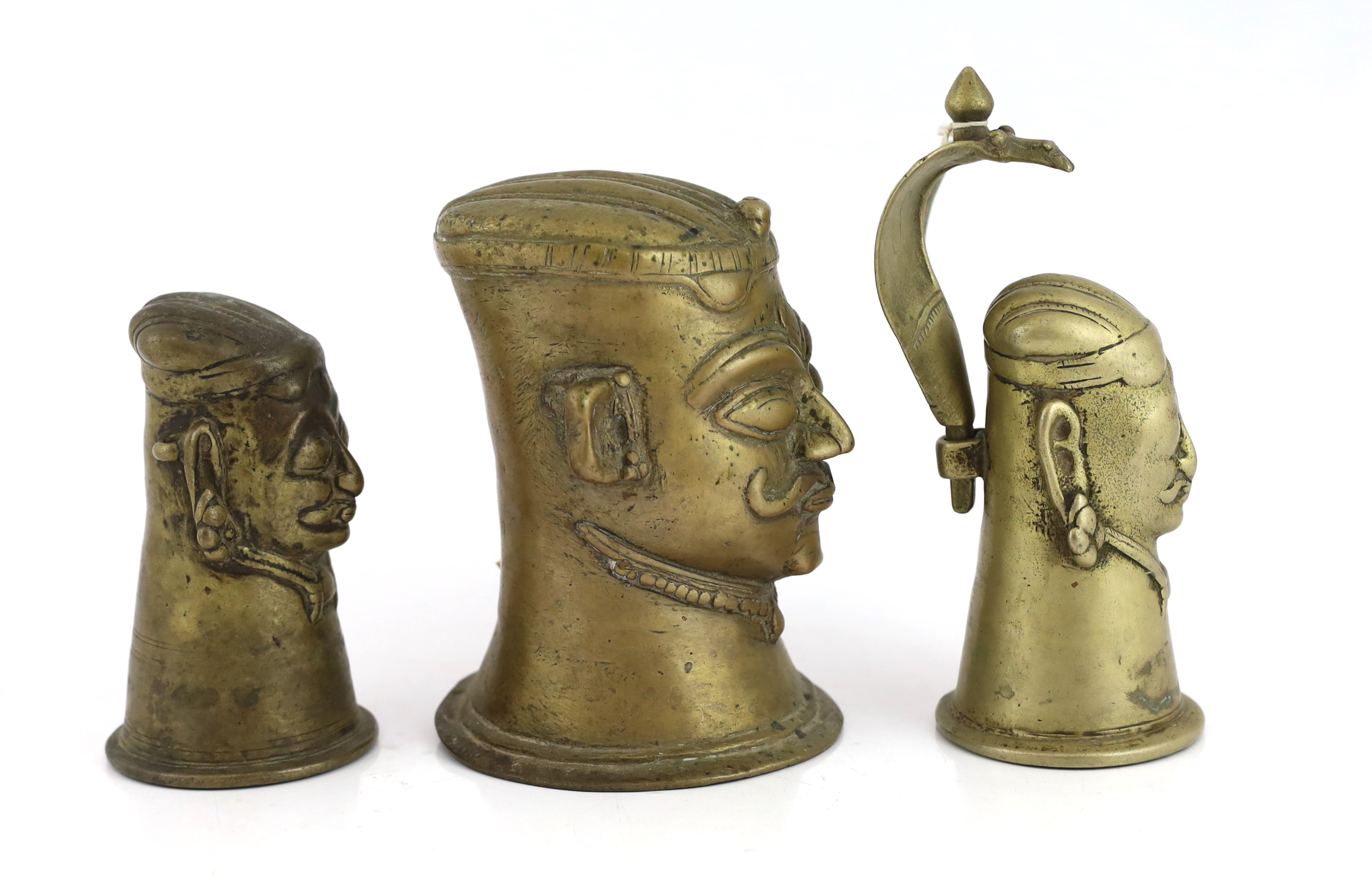 A group of three brass alloy Shiva Mukhalingam, Southern India, 16th-18th century, each depicting a Shiva head, wearing his characteristic moustache, earrings and matted hair, one example surmounted by a removable Naga (